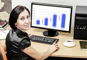 Woman in office with computer smiling