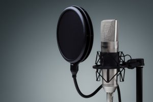 Studio microphone and pop shield on mic stand against gray background