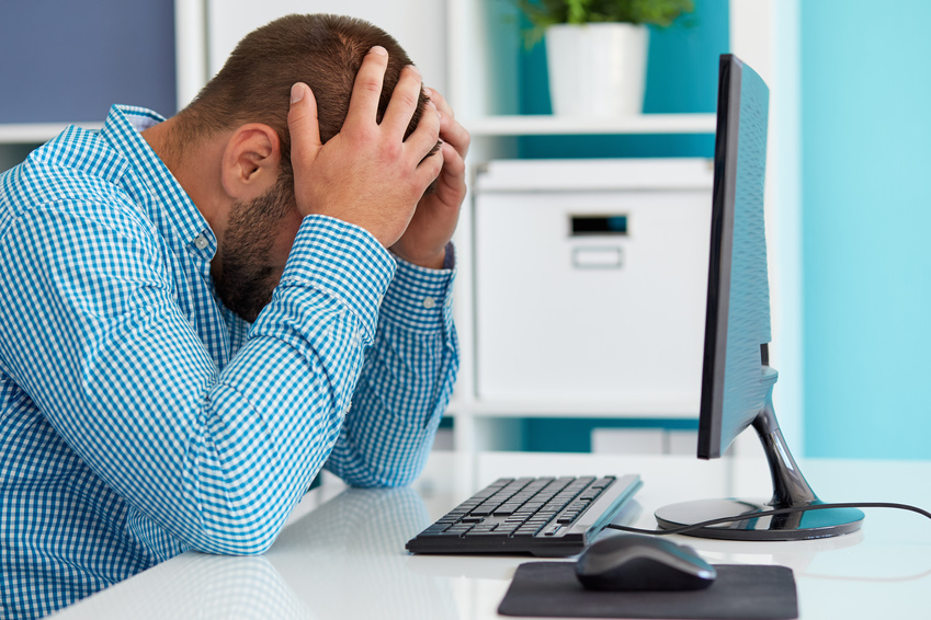 man at computer, frustrated with his hands on his head