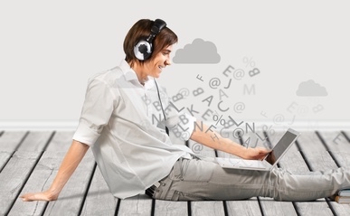 man listening to his headphones and looking at his laptop