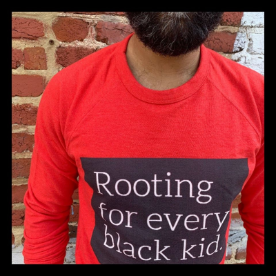 Man wearing shirt stating "Rooting for every black kid."