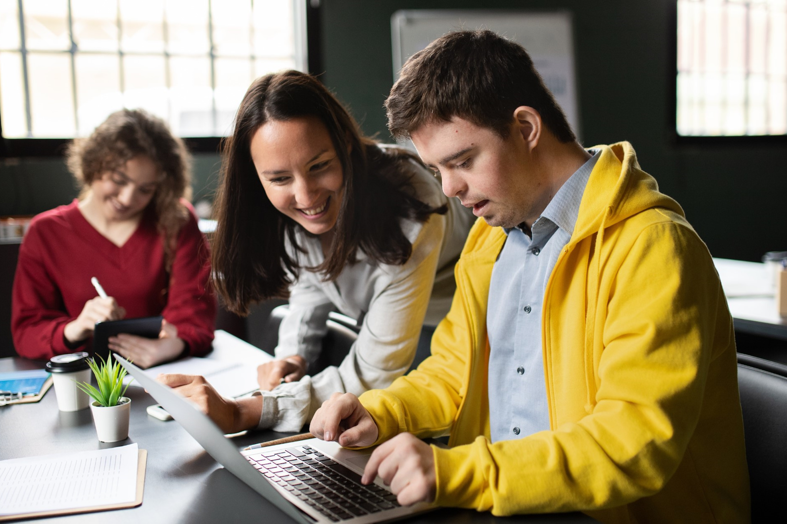 three people working working and training at a desk